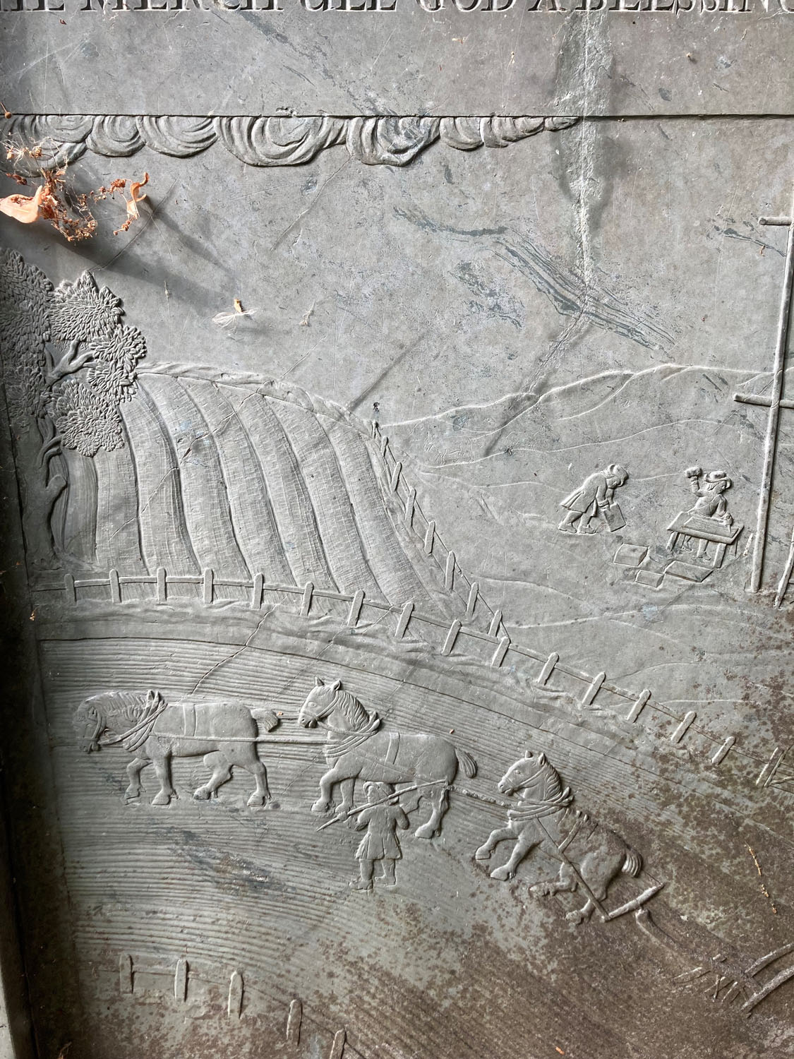 An ornate carving into swithland slate, depicting agricultural scenes