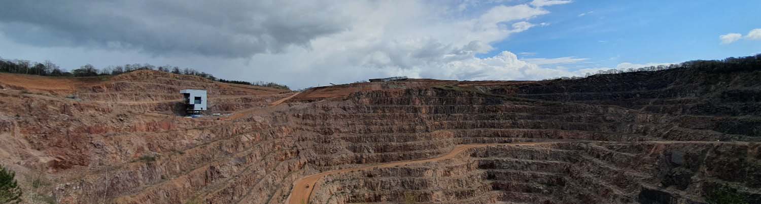 A landscape view of Mountsorrel Quarry. There are ledges of pink coloured rock.