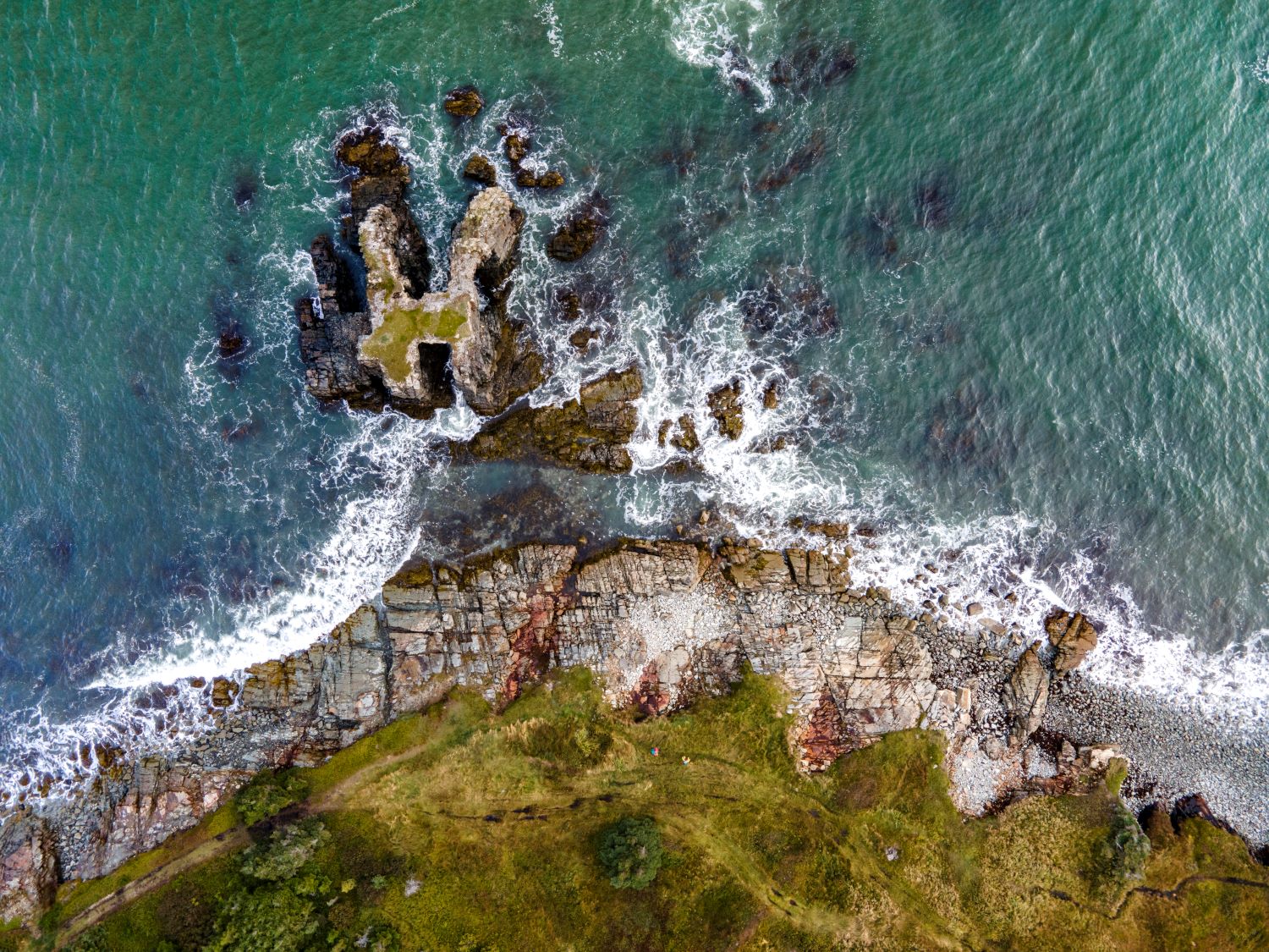 A view down from a drone, showing rocks around an area of coastline