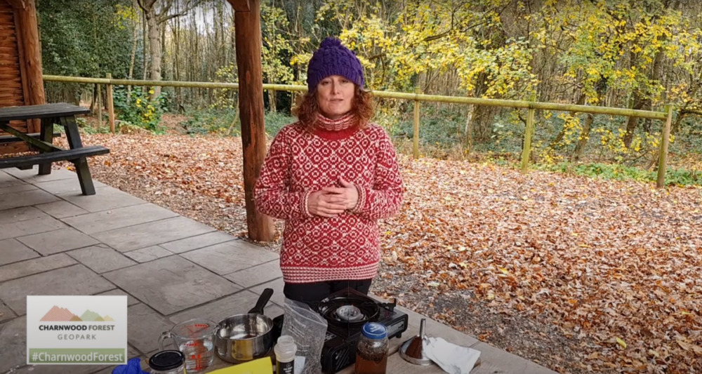 A lady stands in front of some equipment, ready to make some oak gall ink.