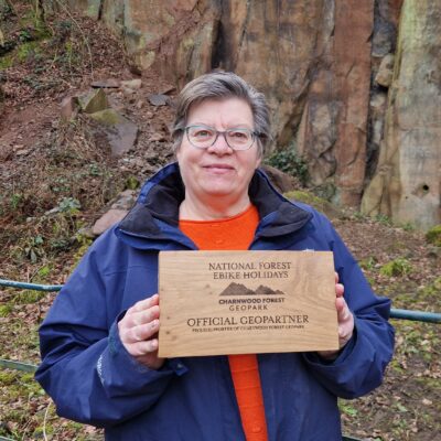 Sue from National Forest E-Bike Holidays stands with her new wooden Geopartner sign
