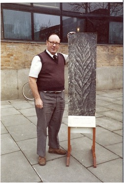 Trevor Ford stands next to an enlarged photograph of Charnia.