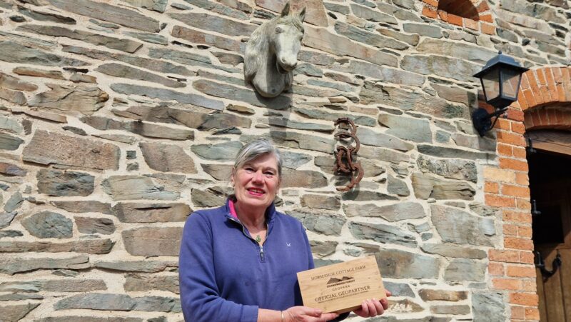 Linda with a wooden sign at Horseshoe Cottage Farm